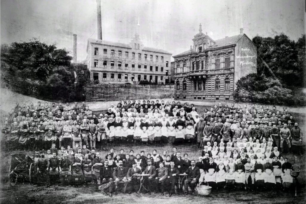 Photographie de l'usine et ses employés vers 1890-1895 Photographie de 1890-1895, où figure le premier atelier de Rodi & Wienenberger situé à droite du cliché, ainsi que les employés de l'usine.